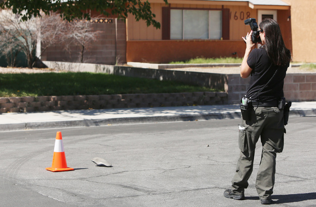 A crime scene and evidence photographer takes a picture of a single shoe in the street near a home invasion in the 1700 block of Breezewood Drive, near Vegas and North Torrey Pines drives, Thursda ...