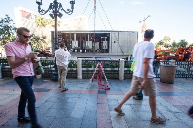 Part of a new central plant, center, is prepared to be lifted by a crane while pedestrians walk by as renovations go on at the Best Western Plus Casino Royale in Las Vegas on Wednesday, Sept. 17, ...