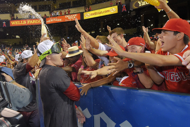 Los Angeles Angels' Mike Trout celebrates with fans after they clinched the American League West division following their baseball game against the Seattle Mariners, Wednesday Sept. 17, 2014, in A ...