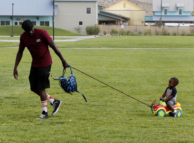 Lavelle Bonds, left, leads his son Messiah Bonds, 1, right, out of the rain and wind at Wilbur and Theresa Faiss Park in the southwest part of the Las Vegas valley on Sunday, Sept. 7, 2014. Rain a ...