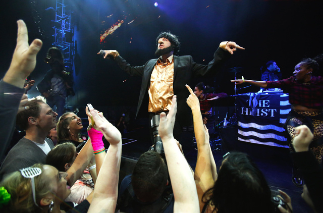 In this photo taken May 16, 2014, Macklemore of the group Macklemore & Ryan Lewis strikes a pose as he performs "Thrift Shop" to a mob of waving fans during Vivid: Spectacle Opening Night Party at ...
