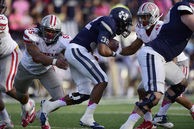 Utah State's Joe Hill (32) carries against Rebels linebacker Tau Lotulelei (55) and defensive back Peni Vea (42) on Oct. 25, 2014. The Aggies defeated the Rebels 34-20. (Ron Chenoy-USA TODAY Sports)