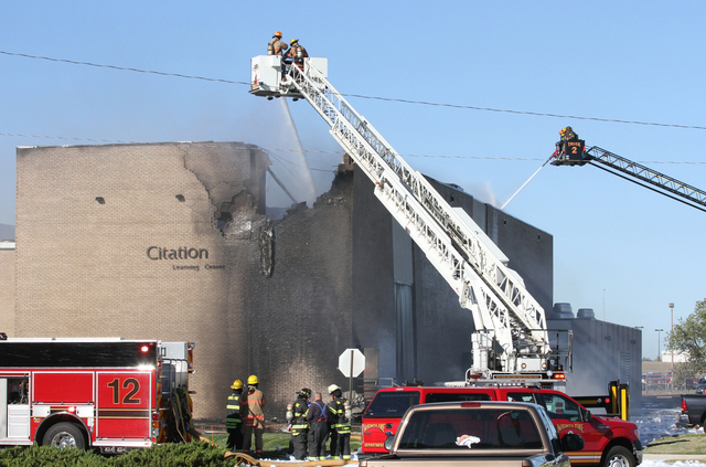 Firefighters try to put out a fire in a building near Mid-Continent Airport in Wichita, Kansas, Thursday, Oct. 30, 2014, shortly after a small plane crashed into the building, killing several peop ...