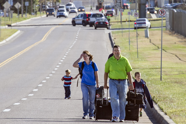 Scott Gatzulis and his family, returning to Wichita from a Hawaii vacation, walk to their car at Mid-Continent Airport in Wichita, Kansas, Thursday, Oct. 30, 2014, after a small plane crashed into ...