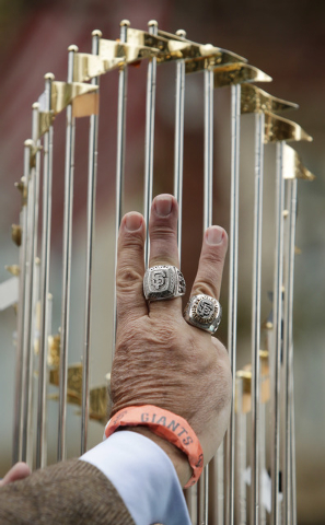 World Series rings adorn two fingers of a hand in front of one the San Francisco Giants' World Series trophies during the victory parade for the 2014 baseball World Series champions, Friday, Oct.  ...