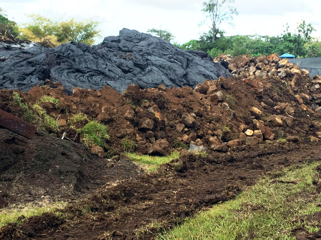 This Oct. 30, 2014 photo from the U.S. Geological Survey shows where lava flow has come into contact and inflated against an artificial berm, to a level much higher than that of the berm, on priva ...