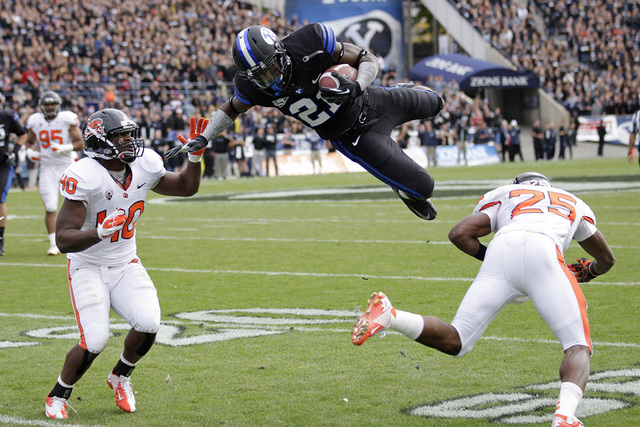 Brigham Young running back Jamaal Williams (21) soars after taking a hit from Oregon State safety Ryan Murphy (25) while teammate Michael Doctor (40) looks on in the first quarter during an NCAA c ...