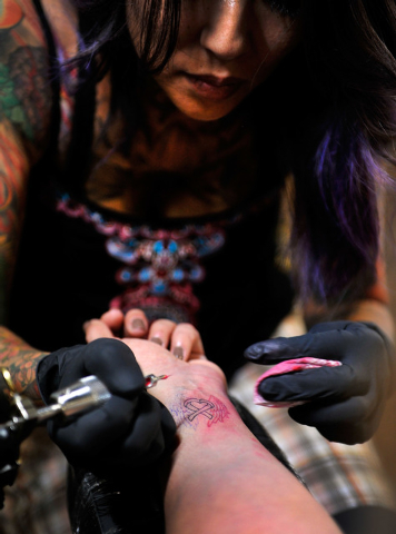 Tattoo artist Valerie Noda creates a tattoo on the wrist of Carmen Lomeli  at Noda's shop, Blue Buddha Tattoo in Las Vegas on Monday, Oct. 6, 2014.  Lomeli's mother died from breast