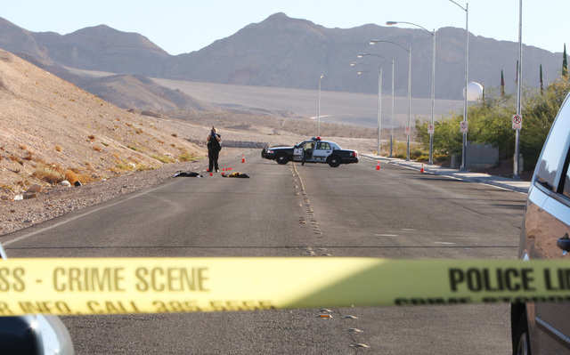 A Las Vegas police accident scene photographer takes a picture at the accident scene Friday, Oct. 31, 2014, near Sahara Avenue and Hollywood Boulevard. Two men sitting on the trunk of a car driven ...