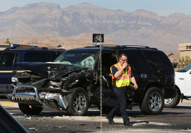 Las Vegas police officer walks past the accident scene where a Clark County fire truck and an SUV collided at the intersection of Blue Diamond Road and Durango Drive on Friday, Oct. 31, 2014. Four ...