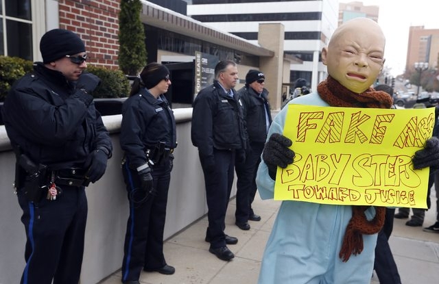 A demonstrator marches past a line of police officers during a protest over the shooting death of Michael Brown in Clayton, Missouri, November 17, 2014. Several dozen demonstrators took to the str ...