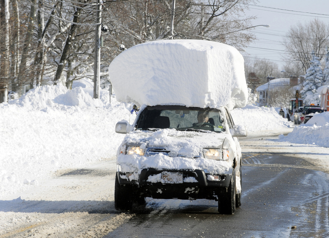 A vehicle with a large chunk of snow on its top drives along Route 20 after digging out after a massive snow fall in Lancaster, N.Y., Wednesday, Nov. 19, 2014. The Buffalo area found itself buried ...