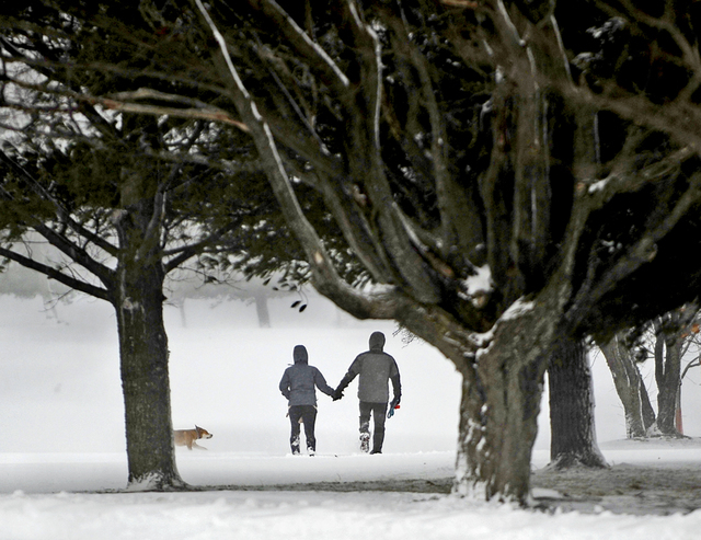A couple take their dog for a walk on the trails through the Watertown Golf Club in Watertown, N.Y., on Thursday, Nov. 20, 2014.  A new blast of lake-effect snow pounded Buffalo for a third day pi ...