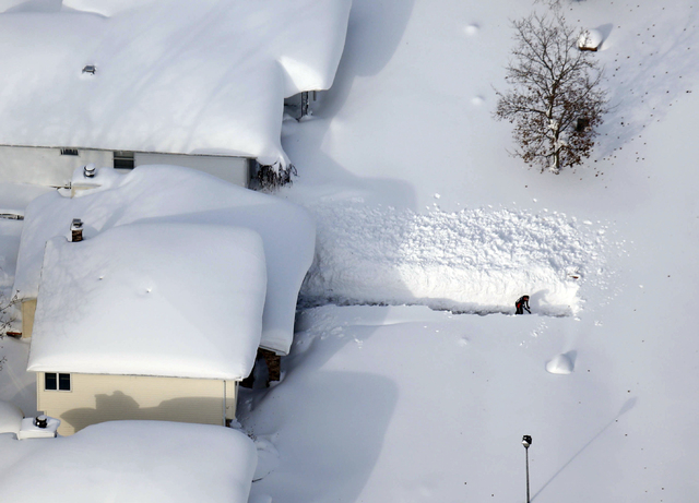 A man digs out his driveway in Depew, N.Y., Wednesday, Nov. 19, 2014. The Buffalo area found itself buried under as much as 7 feet of snow by Thursday. (AP Photo/The Buffalo News, Derek Gee)