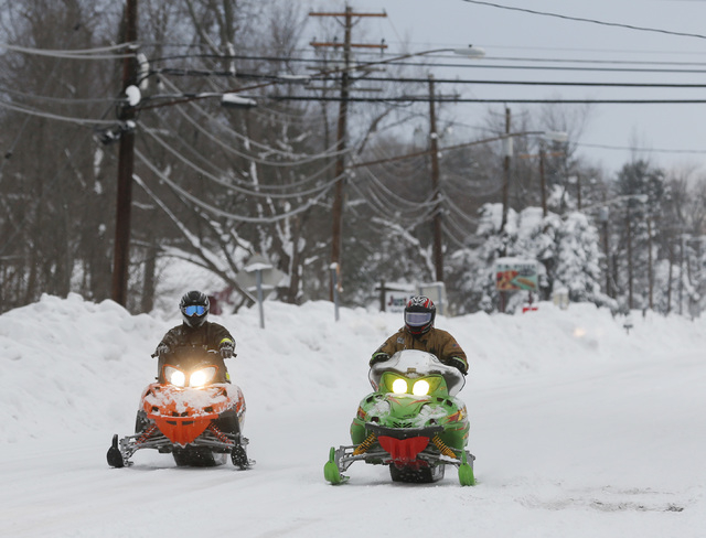 Volunteer firefighters ride snowmobiles alone Clinton Street on Thursday, Nov. 20, 2014, in West Seneca, N.Y. A new blast of lake-effect snow pounded Buffalo for a third day piling more misery on  ...