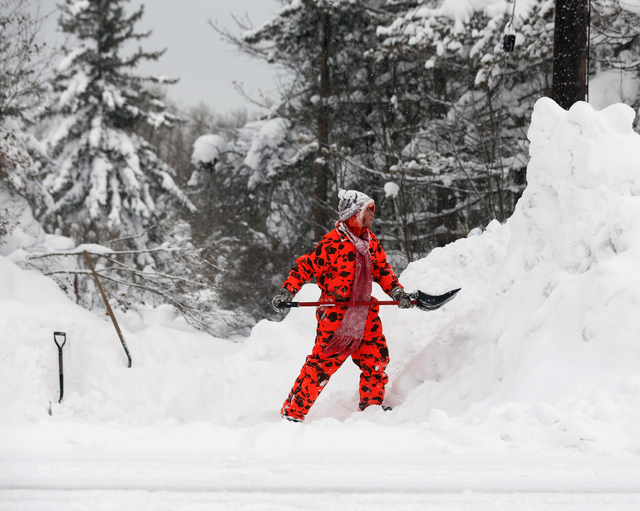 Karen McRae clears snow from her driveway on Thursday, Nov. 20, 2014, in West Seneca, N.Y. A new blast of lake-effect snow pounded Buffalo for a third day, piling more misery on a city already bur ...
