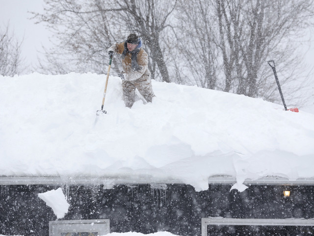 Tom Mudd clears snow from the roof of his house on Thursday, Nov. 20, 2014, in Cheektowaga, N.Y. A new blast of lake-effect snow pounded Buffalo for a third day piling more misery on a city alread ...