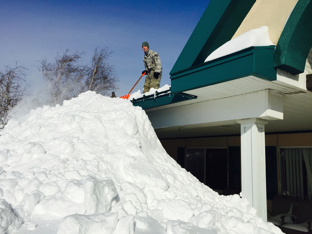 An airman with the New York Air National Guard shovels snow off the roof of the Eden Heights Assisted Living Facility in West Seneca, N.Y., Wednesday, Nov. 19, 2014. A new blast of lake-effect sno ...