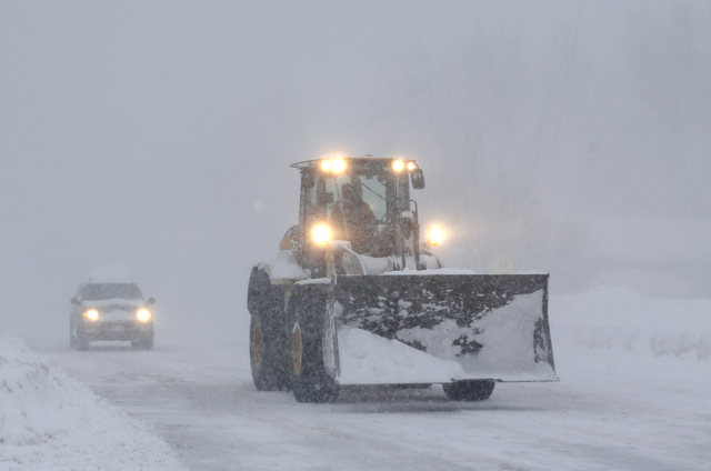 A front loader drives through a snowstorm along Union Road on Thursday, Nov. 20, 2014, in West Seneca, N.Y. A new blast of lake-effect snow pounded Buffalo for a third day, piling more misery on a ...