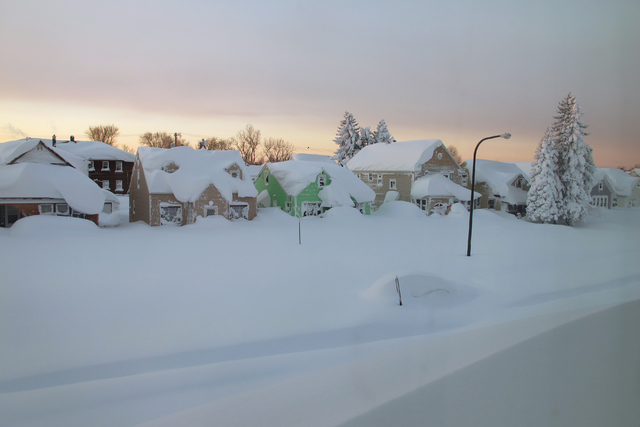 Snow covers a street at daybreak Wednesday, Nov. 19, 2014, in south Buffalo, N.Y. Buffalo-area officials are getting help from a neighboring county in their efforts to clear roads and provide emer ...