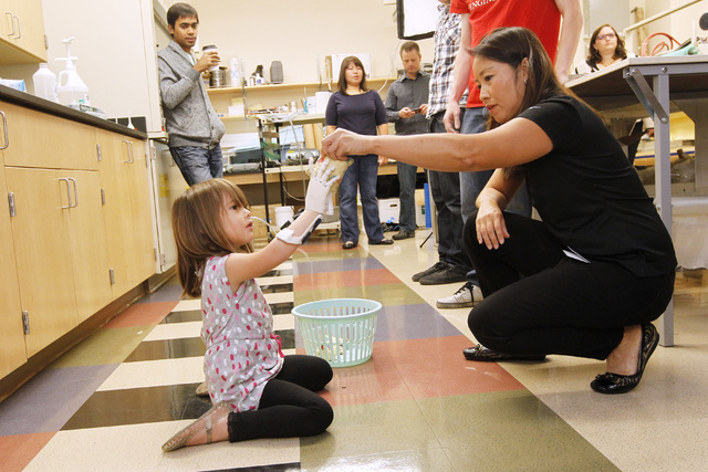 Occupational therapist Cynthia Lau hands a bean bag to Hailey Dawson to test her new prosthetic hand Thursday, Oct. 30, 2014 at UNLV. (Sam Morris/Las Vegas Review-Journal)