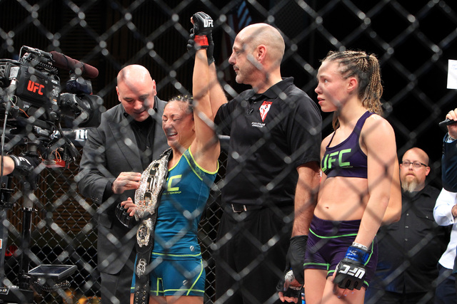 Carla Esparza smiles as Dana White places a championship belt on her shoulder after defeating Rose Namajunas their strawweight fight at The Ultimate Fighter finale Friday, Dec. 12, 2014 at the Pal ...