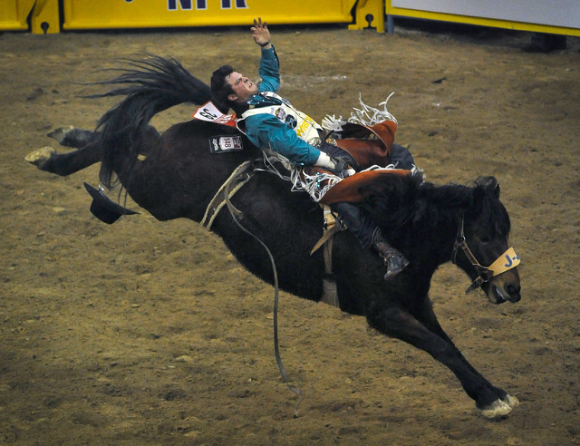 Richmond Champion of The Woodlands, Texas rides Painted Brush as he competes in the bareback riding event during the ninth go-round of the National Finals Rodeo at the Thomas & Mack Center on Frid ...