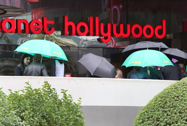 Tourists holding umbrellas stand outside Planet Hollywood Resort and Casino on Las Vegas Boulvard as heavy rain approaches the Las Vegas Valley on Friday, Dec. 12, 2014. A weather system that is b ...