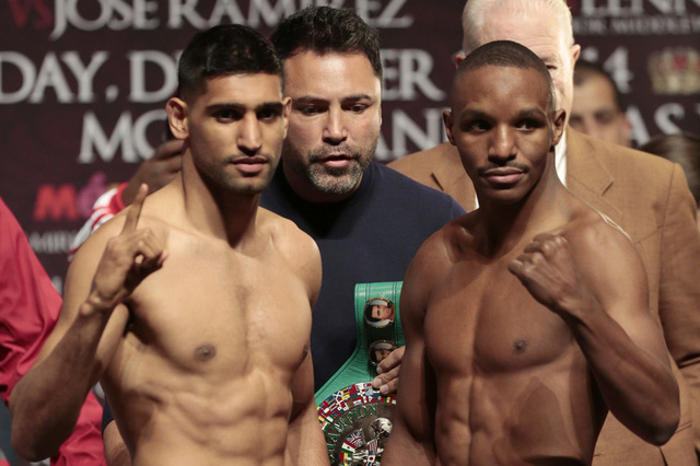 Promoter Oscar De La Hoya, center, holds the title belt  while Amir Khan, left, and Devon Alexander pose during the official weigh-in for their Saturday fight at the MGM Grand Garden Arena in Las  ...