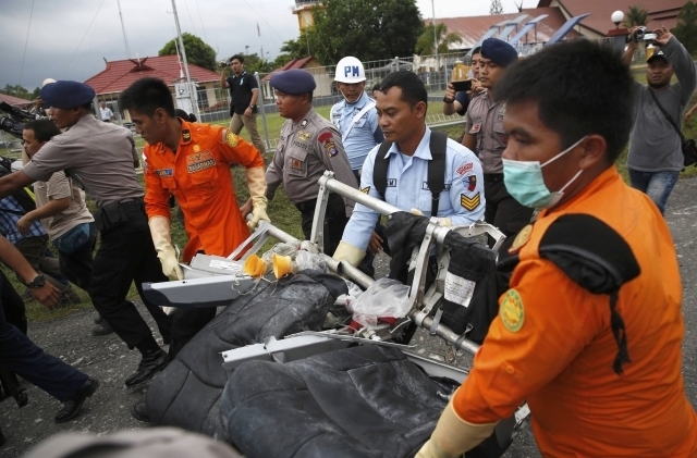 Parts of AirAsia QZ8501, recovered from the Java Sea, are carried by Indonesian Airforce and Search and Rescue crew after they were offloaded from a U.S. Navy helicopter at the airport in Pangkala ...