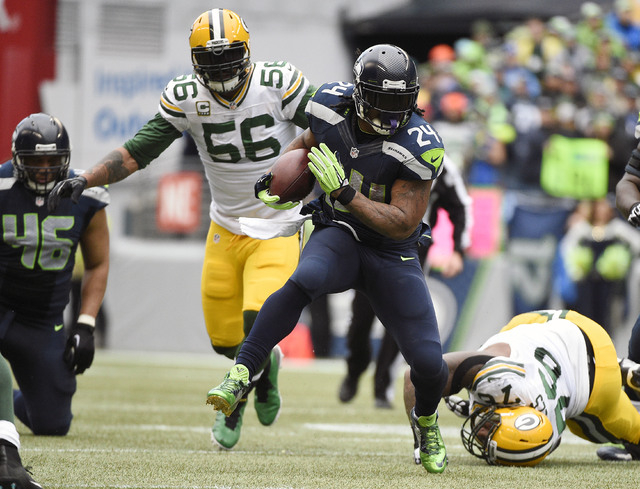 January 18, 2015; Seattle, WA, USA; Seattle Seahawks running back Marshawn Lynch (24) runs the ball ahead of  Green Bay Packers outside linebacker Julius Peppers (56) and defensive end Mike Daniel ...