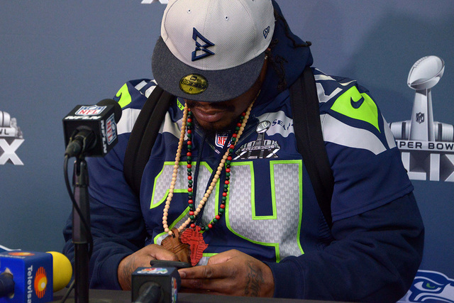 Jan 29, 2015; Phoenix, AZ, USA; Seattle Seahawks running back Marshawn Lynch (24) sets timer on his cell phone at start of press conference at Arizona Grand in advance of Super Bowl XLIX. (Kirby L ...