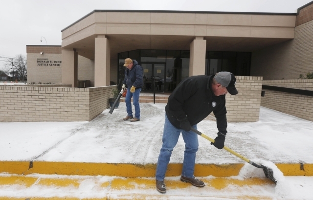 Stephenville county employees clear sleet and ice from the sidewalk outside the courthouse after the capital murder trial of former Marine Cpl. Eddie Ray Routh was postponed, in Stephenville, Texa ...