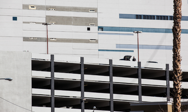 People on top of a parking garage wait around for the remaining portion of The Clarion Hotel and Casino to be taken down, after an early-morning implosion failed to fully bring down the building a ...