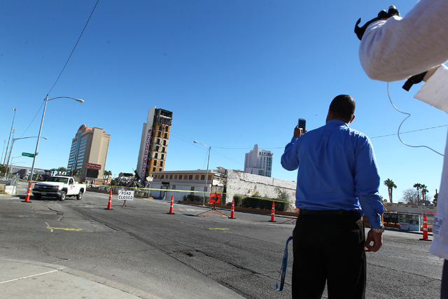 People watch as crews prepare to topple over the remaining portion of The Clarion hotel-casino, after an early-morning implosion failed to fully bring down the building at 305 Convention Center Dr ...