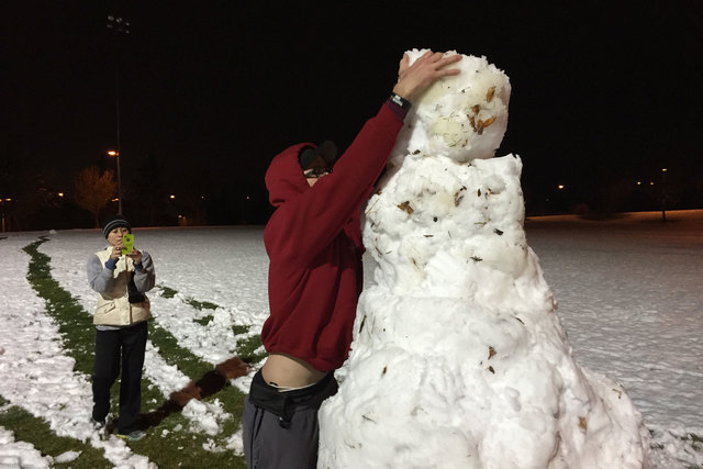 Will Swope puts the head on a snowman early Monday, Feb. 23, 2015, while Catherine Saenz takes a photo at the Vistas Park football field in Las Vegas. (Keith Rogers/Las Vegas Review-Journal)