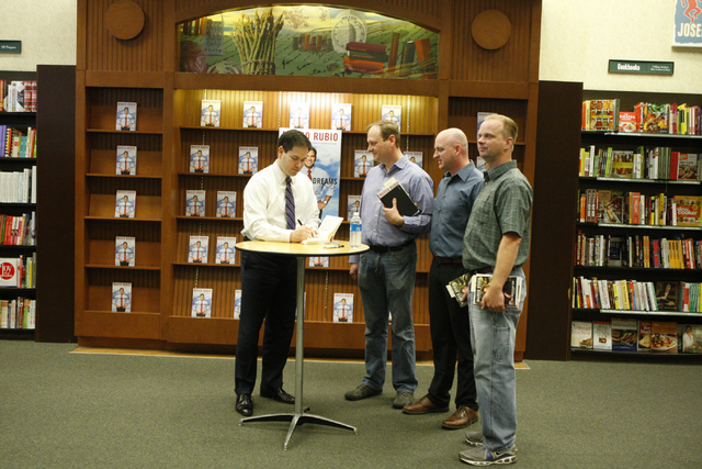 U.S. Sen. Marco Rubio, R-Fla., from left, signs a copy of a book for his childhood friends from left, Bryan Thiriot, and his brothers Bryce, and Nathan during a book signing of his book, American ...