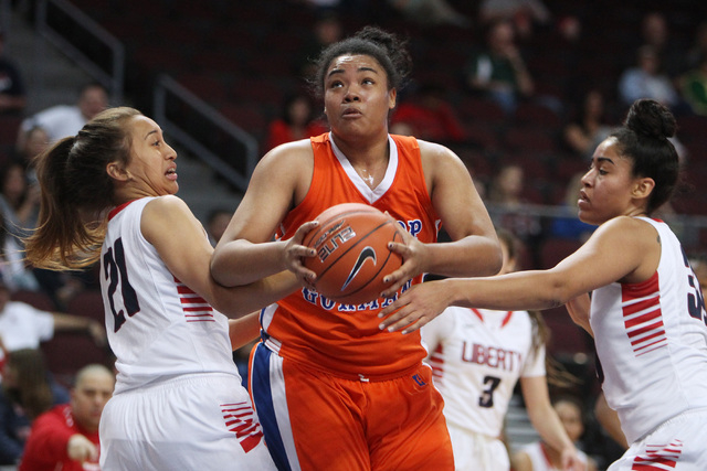 Bishop Gorman forward Raychel Stanley drives between Liberty guard Kaily Kaimikaua, left, and forward Paris Strawther during their Division I state semifinal game Thursday, Feb. 26, 2015, at the O ...