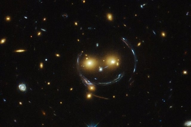 A massive galaxy cluster known as SDSS J1038+4849 appears to be smiling at the Hubble Telescope, which captured the two glowing yellow "eyes" and "smile." (CNN)