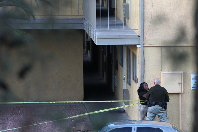 A Las Vegas police officer speaks to an unidentified woman at the Siegel Suites apartments where Las Vegas police officers investigate a shooting near the intersection of E. Twain Avenue and Swens ...