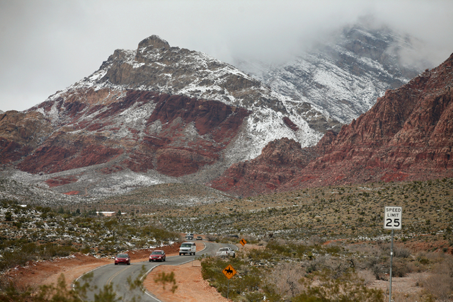 Cars travel along Calico Basin Road and snowfall can be seen at Red Rock Canyon National Conservation Area Monday, Feb. 23, 2015, in Las Vegas. According to Las Vegas police, three hikers were rep ...