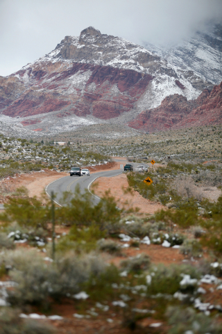 Cars travel along Calico Basin Road and snowfall can be seen at Red Rock Canyon National Conservation Area Monday, Feb. 23, 2015, in Las Vegas. According to Las Vegas police, three hikers were rep ...