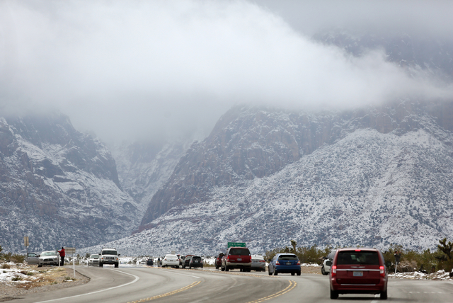Cars travel along U.S. Route 159 and people stop to look at the snow at Red Rock Canyon National Conservation Area Monday, Feb. 23, 2015, in Las Vegas. According to Las Vegas police, three hikers  ...