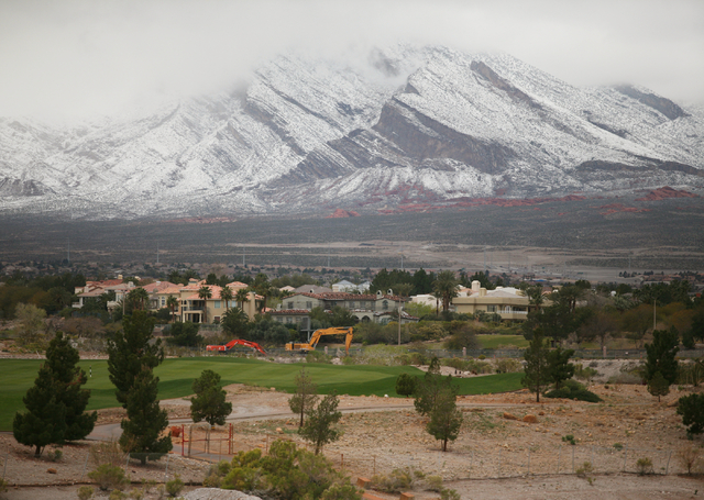 Snowfall can be seen at Red Rock Canyon National Conservation Area, back, from Angel Park Golf Club in Summerlin Monday, Feb. 23, 2015. According to Las Vegas police, three hikers were reported st ...