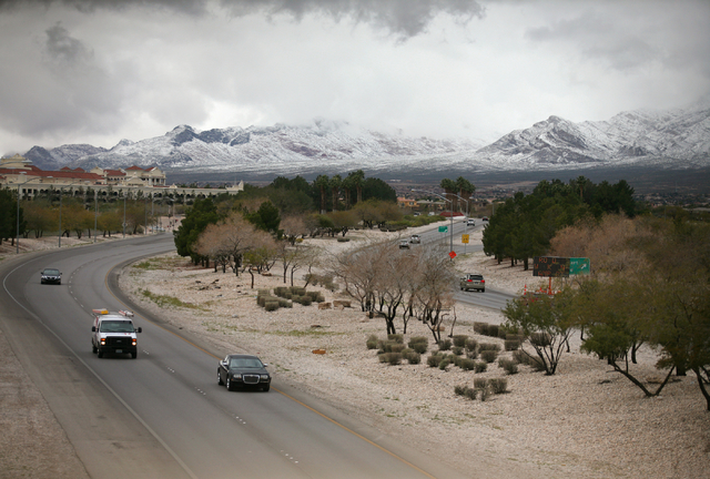 Cars travel along Summerlin Parkway and snowfall can be seen at Red Rock Canyon National Conservation Area Monday, Feb. 23, 2015, in Las Vegas. According to Las Vegas police, three hikers were rep ...