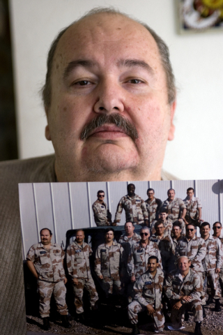 Former Area 51 worker Fred Dunham holds up a photograph while standing in his home Wednesday, Aug. 13, 2008, that depicts himself, standing at left, with several of his coworkers in 1988. Due to D ...