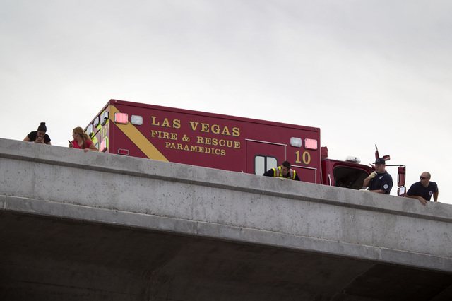 Emergency personnel and onlookers stand near where a woman jumped from an overpass at the Spaghetti Bowl on Tuesday, March 17, 2015. Police were notified at 5:34 pm. about the incident, which stal ...