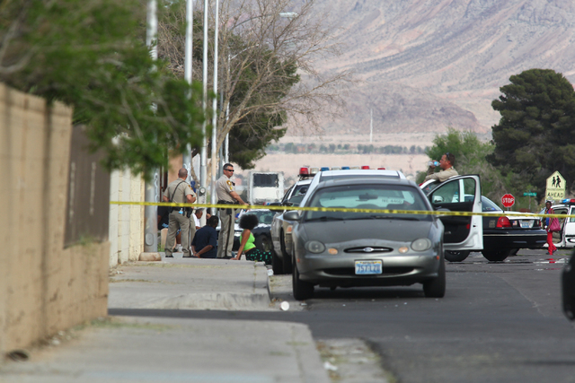 Detained people are seen as Las Vegas police respond to a barricade situation after reports of a suspect firing at an occupied vehicle, at the intersection of Sandy Lane and Alto Avenue in Las Veg ...