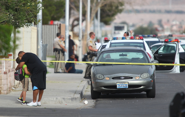 A man hugs a young girl as Las Vegas police respond to a barricade situation after reports of a suspect firing at an occupied vehicle, at the intersection of Sandy Lane and Alto Avenue in Las Vega ...