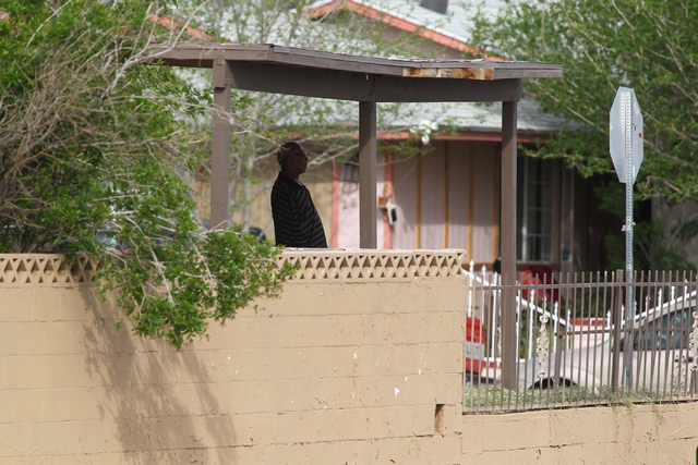 A man watches as Las Vegas police respond to a barricade situation after reports of a suspect firing at an occupied vehicle, at the intersection of Sandy Lane and Alto Avenue in Las Vegas on Tuesd ...